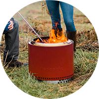 People standing around a red solo stove.